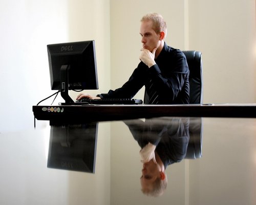 Man adjusting monitor height at desk